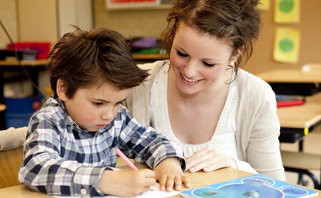 teacher working with a preschooler at a table