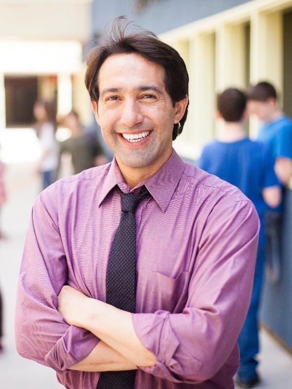 male school counselor smiling outside of a school building