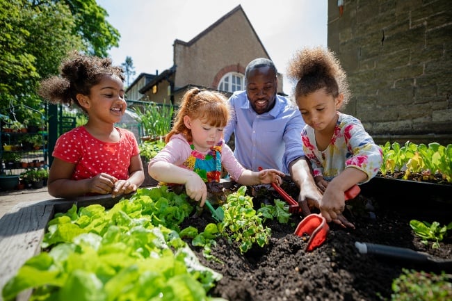 early childhood teacher working in the garden with children