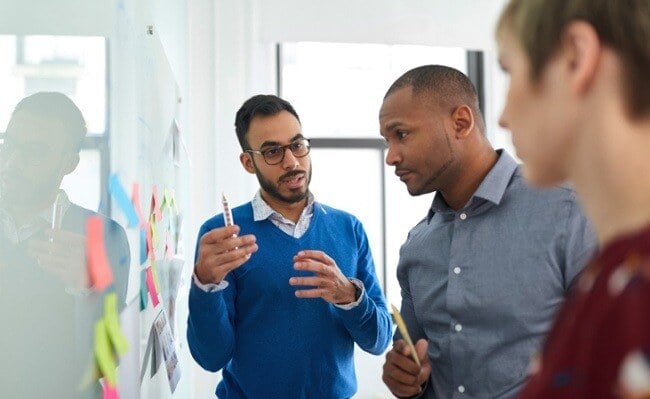 men in a discussion at a whiteboard